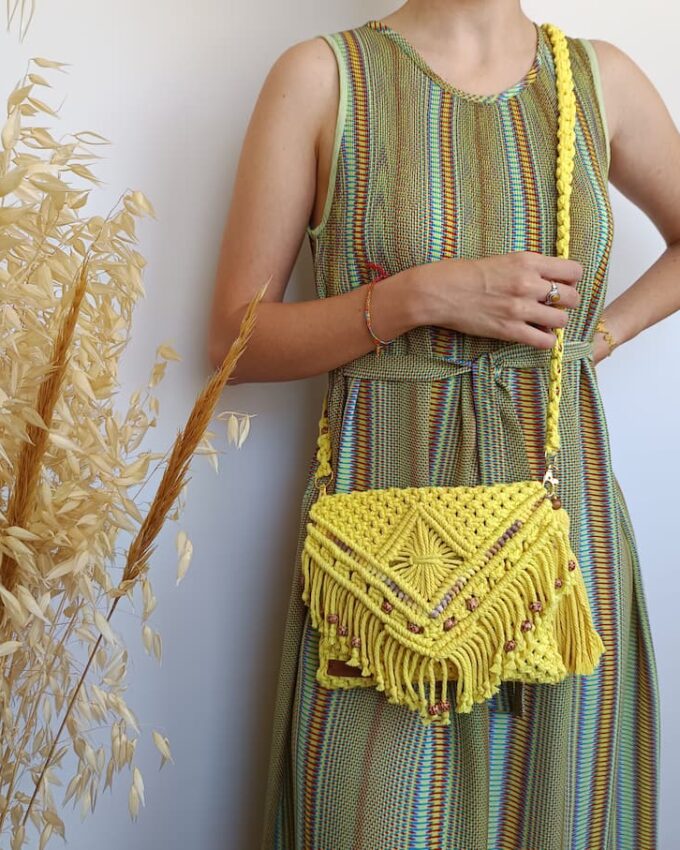 Bolso amarillo de macramé con flecos y bolitas de madera en la solapa