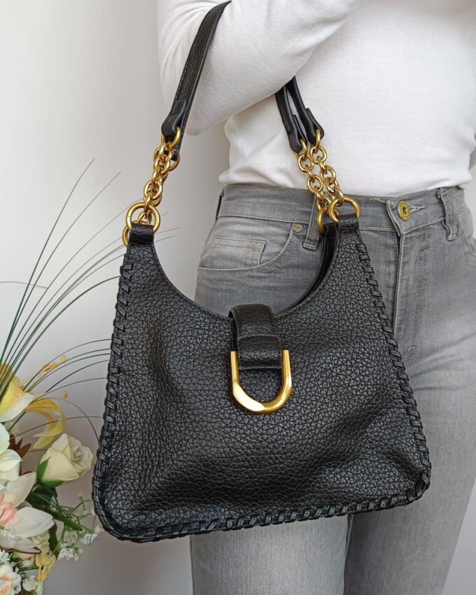 Bolso negro de cuero sintético rugoso con hebilla y asas doradas