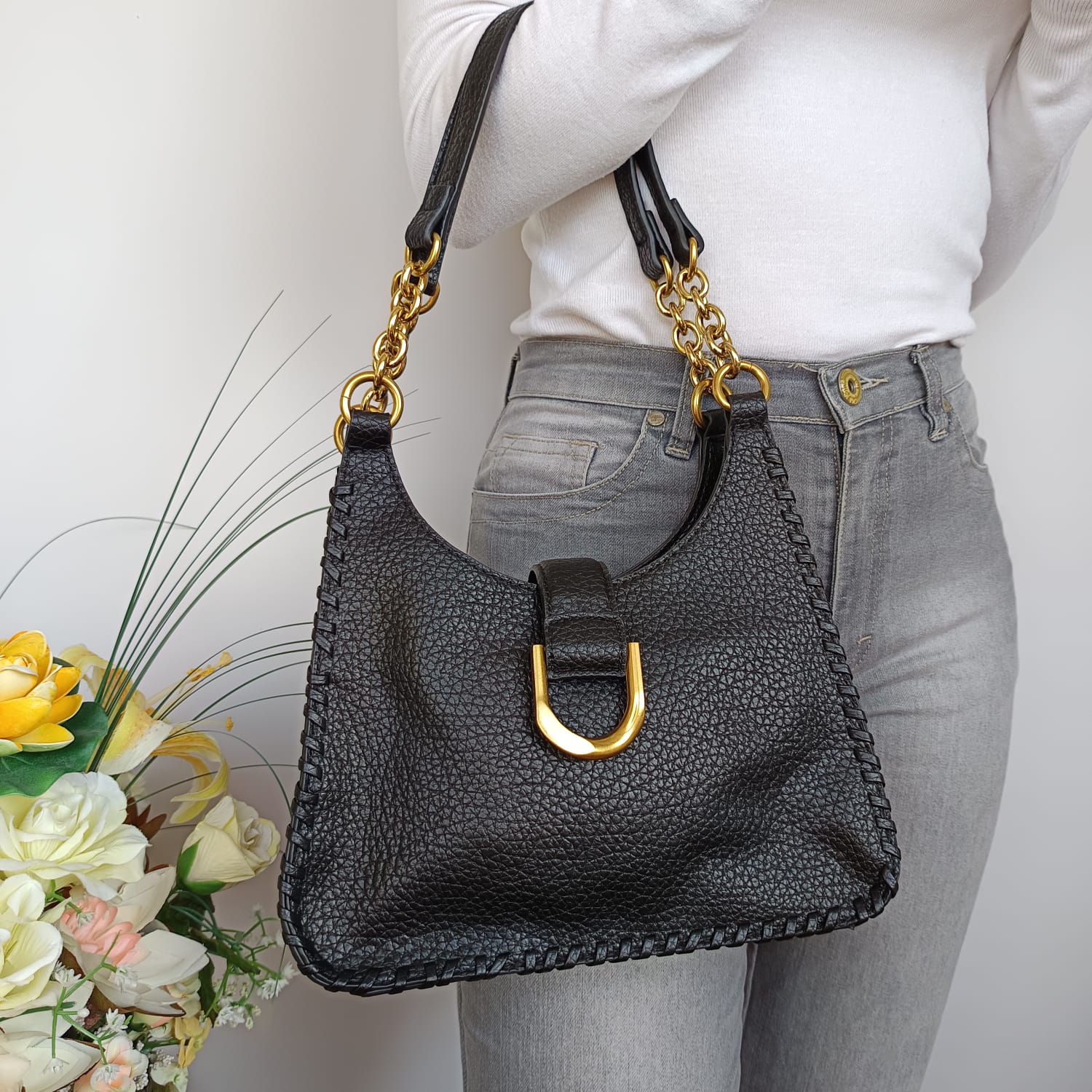 Bolso negro de cuero sintético rugoso con hebilla y asas doradas