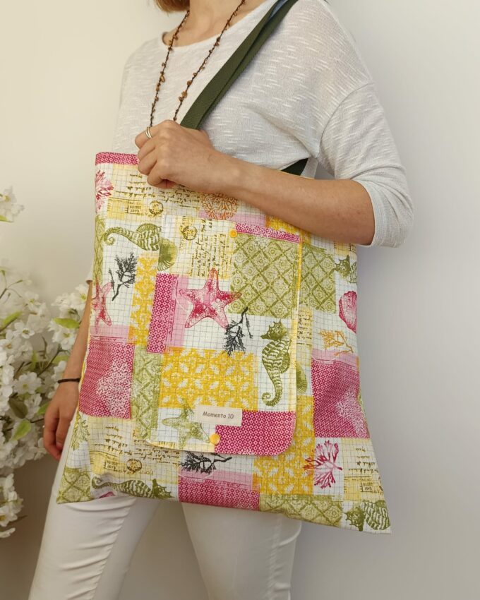 Bolsa plegable de tela resinada con diseño geométrico multicolor.