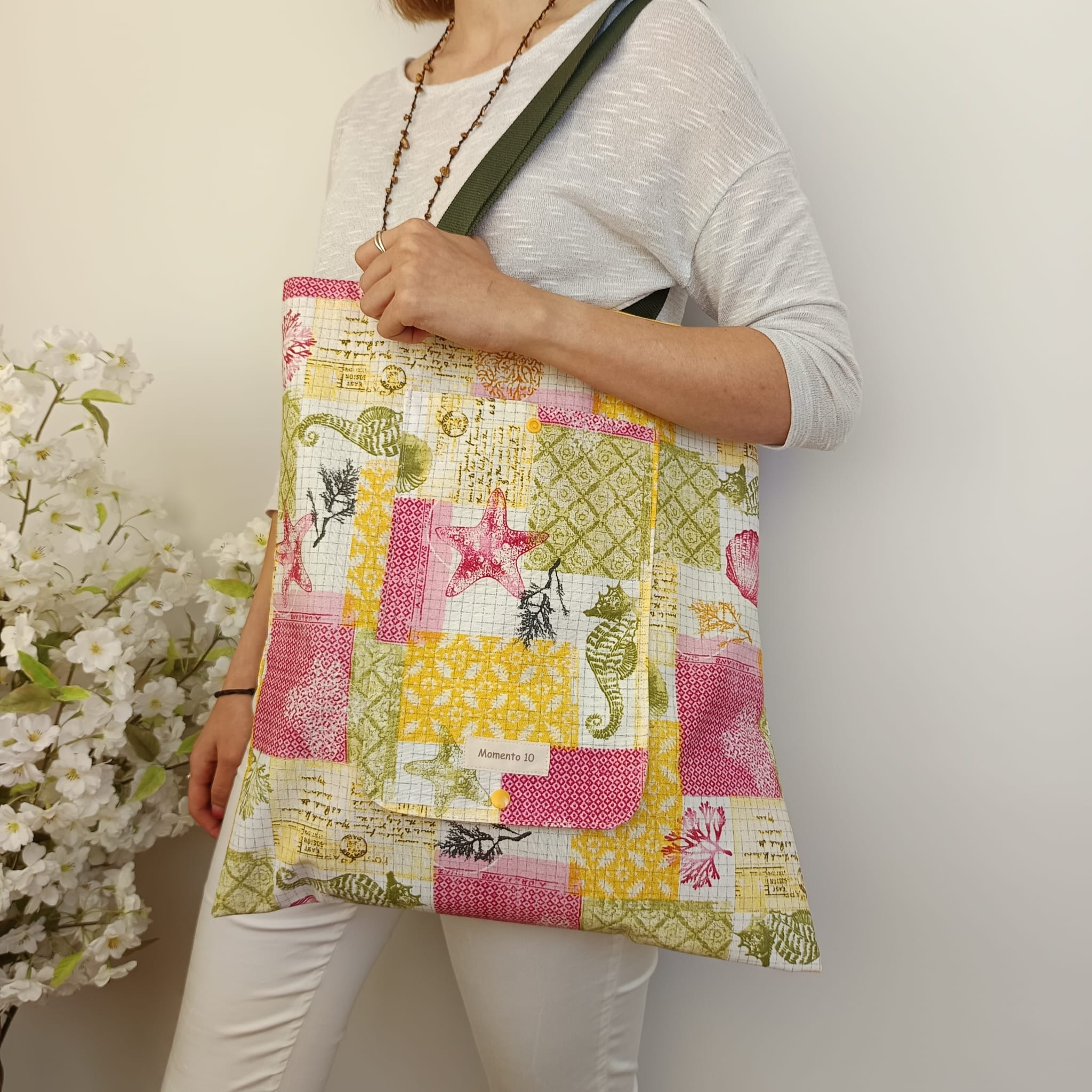 Bolsa plegable de tela resinada con diseño geométrico multicolor.
