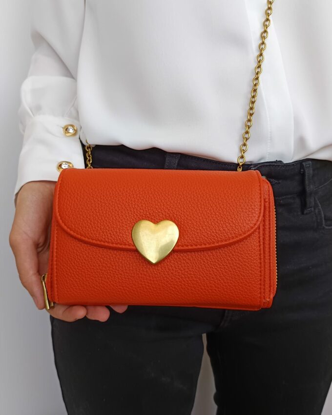 Bolso de polipiel naranja con broche dorado en la solapa y tarjetero