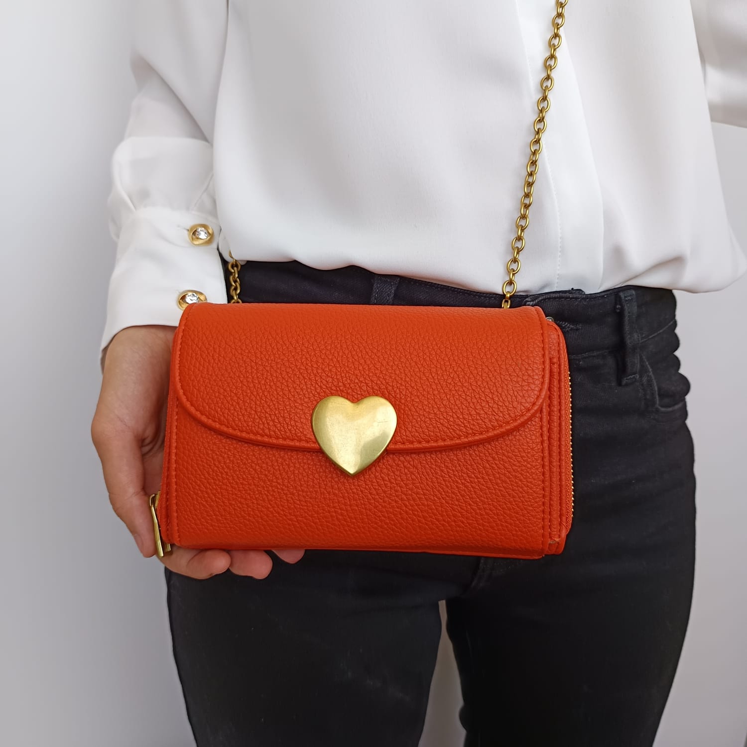 Bolso de polipiel naranja con broche dorado en la solapa y tarjetero